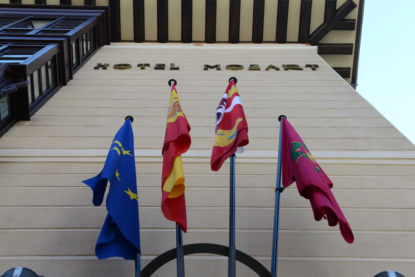 Detalle de la fachada con el letrero del Hotel Mozart Valladolid y banderas oficiales a la entrada.